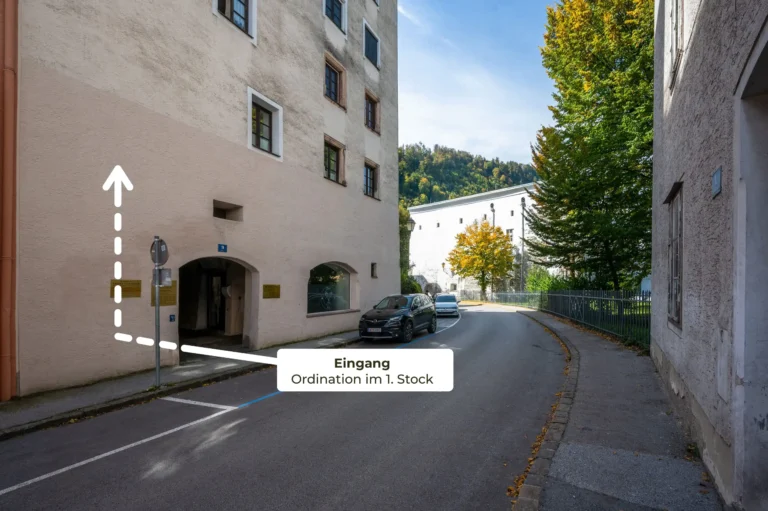Eingangsbereich der Gruppenpraxis Innere Medizin Hallein mit Wegbeschreibung zum Eingang im 1. Stock an einem Altbau in der